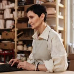 Small business owner in her studio checking her website on a laptop