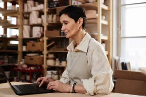 Small business owner in her studio checking her website on a laptop