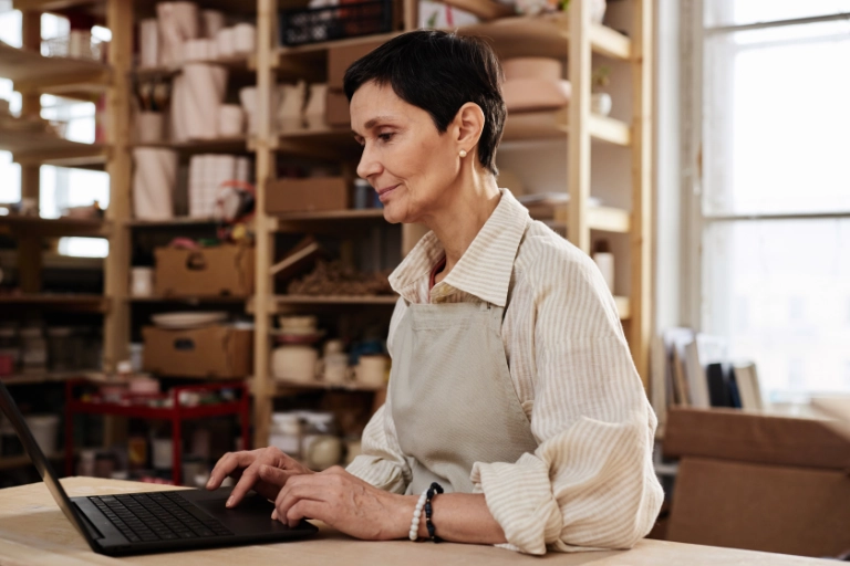 Small business owner in her studio checking her website on a laptop