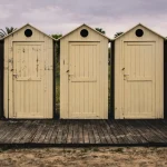 A row of weathered beach cabins with one door left ajar, representing an old website left unsecured.