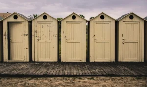A row of weathered beach cabins with one door left ajar, representing an old website left unsecured.