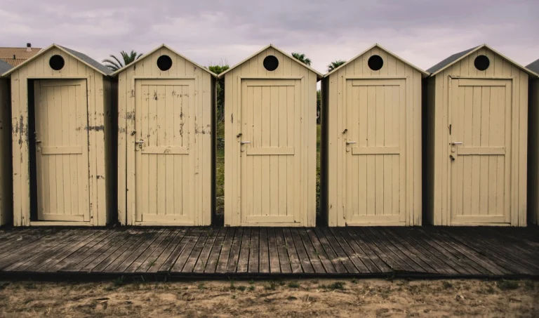 A row of weathered beach cabins with one door left ajar, representing an old website left unsecured.